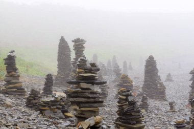Sabah ları sisin içinde denizin çakıl plajındaki taş piramitler