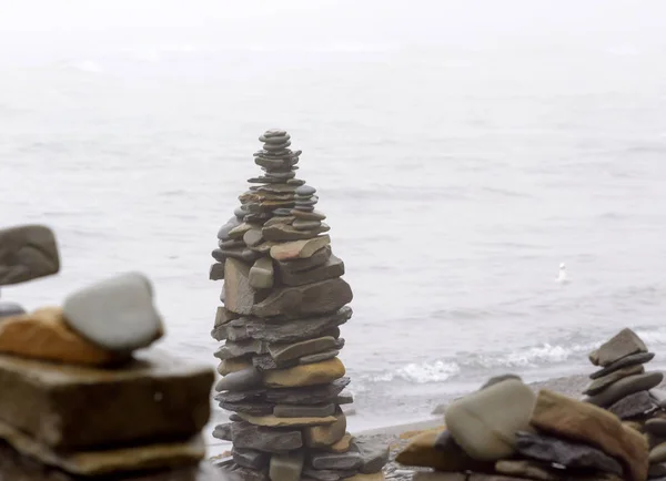 Sabah ları sisin içinde denizin çakıl plajındaki taş piramitler