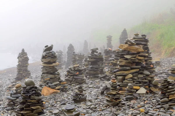 Sabah ları sisin içinde denizin çakıl plajındaki taş piramitler