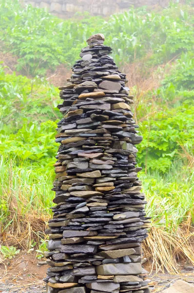 Bulutlu bir sabah yakın denizde bir çakıl plajıüzerinde Taş piramit