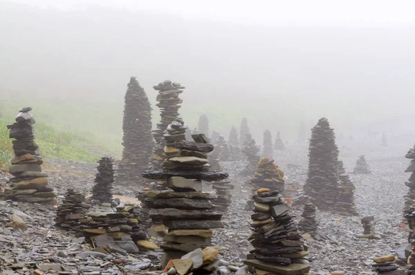 Sabah ları sisin içinde denizin çakıl plajındaki taş piramitler