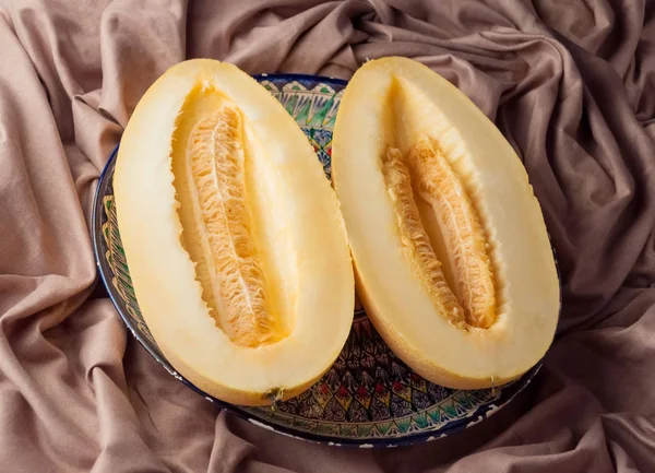 Melon, cut into two lobes, lying on a plate with oriental ornament