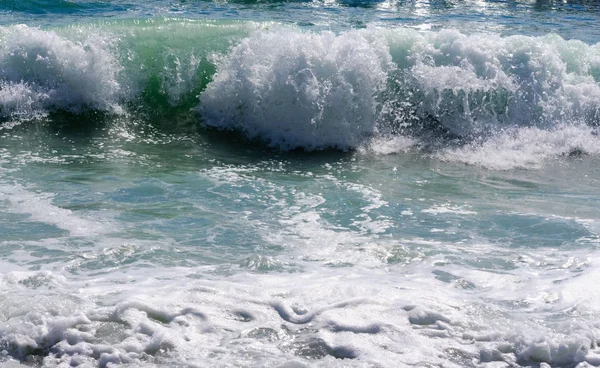 Taşlı sahilde yuvarlanan deniz dalgaları, yakın bir yerde