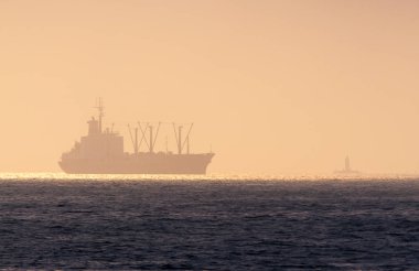 Yolda bir gemi ve akşam karanlığında bir deniz feneri.. 