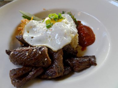 Kalbi Loco Moco yumurta üzerinde kolay, pirinç, kim chee ve beyaz tabakta sıcak sos ile.