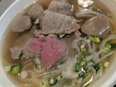 Pho (Vietnam pirinç şehriye çorbası) sığır eti, et topu, soğan ve Frenk soğanı Close-up.