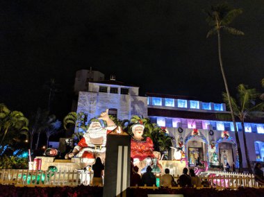 Honolulu - 18 Aralık 2017: Bay ve Bayan Noel sit Honolulu City Light bir parçası olarak gece Honolulu Hale, Belediye Başkanı ofis önünde Hindistan cevizi içki, POI çanta ve Lau lau ışık dayanabiliyor kaplumbağa rakam ile üst şelale insanlar göz
