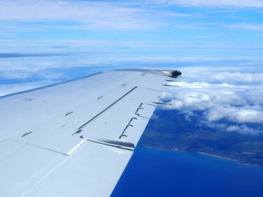 Oahu bulutlu bir ticari jet uçağının kanadı ile Honolulu, Hawaii bırakarak uçağın pencere görünümü gökyüzü yüksek havadan vurdu görünür.