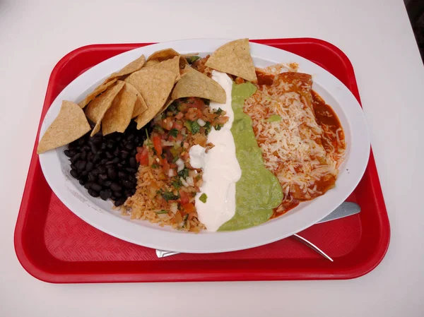 Enchiladas 与西班牙大米 Pico Gallo 酸奶油 Guacamole 和黑豆纸盘与金属叉子 刀在白色桌上 — 图库照片