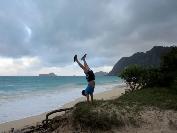 Hombre hace handstand en grassy bluff en Waimanalo playa —  Fotos de Stock
