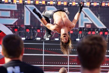 WWE Wrestler Seth Rollins flips in the air off top of the ropes 