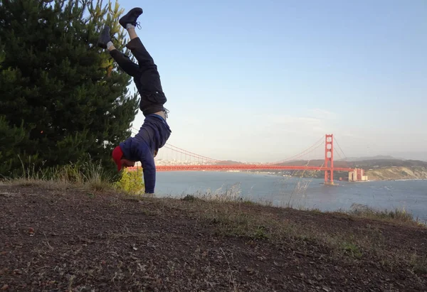 Man Handstands in na colina em frente à Golden Gate Bridge — Fotografia de Stock