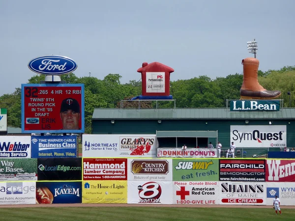Baseball player stands in the outfield with ads on wall includin — Stock Photo, Image