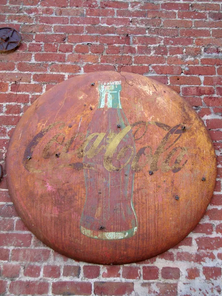 Old Rusted Coca-Cola Sign featuring glass bottle on Red Brick Wa — Stock Photo, Image