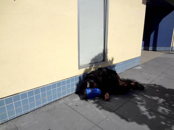 Homeless person sleep on sidewalk spilling into the street with — Stock Photo, Image