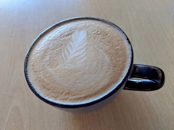 Balck Tasse Cappuccino auf Untertasse mit Blattmuster in Schaumstoff — Stockfoto