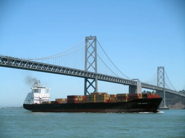Frachtschiff segelt unter der San Francisco Bay Bridge und Insel o — Stockfoto