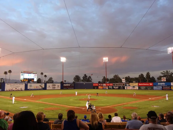 Pitcher throws pitch towards batter at dusk — Stock Photo, Image