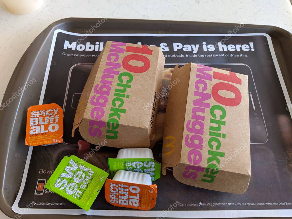 Waikiki - July 19, 2018: Two Ten Piece Chicken McNuggets on a tray with dipping sauces Spicy Buffalo and Sweet and Sour inside a McDonald's store.