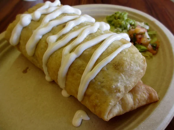 Chimichanga with sour cream on top and guacamole on the side on — Stock Photo, Image