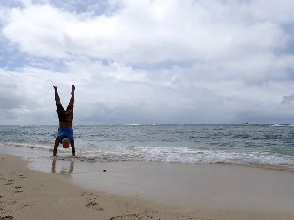 Man Handstand na plaży jak fala roll do brzegu — Zdjęcie stockowe