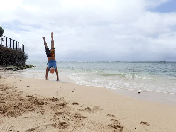 Hombre Handstand en la playa como ola rollo en la costa —  Fotos de Stock