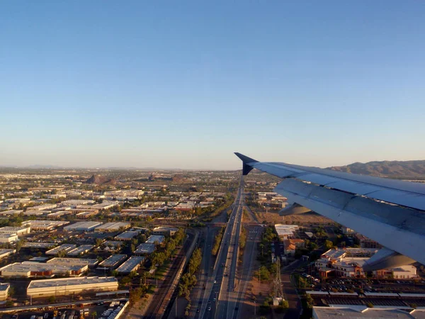 飞机机翼飞过高速公路和建筑物飞入城市 — 图库照片