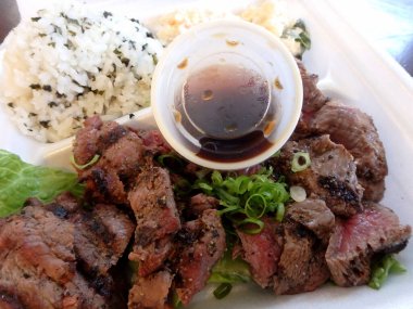 Plastik bir kapta pilav ve acılı soslu pirzola..