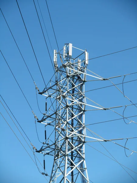 高電圧電源ラインは カリフォルニア州サンノゼの青い空に対してセルタワーと大きな金属ユーティリティポールに交差します — ストック写真
