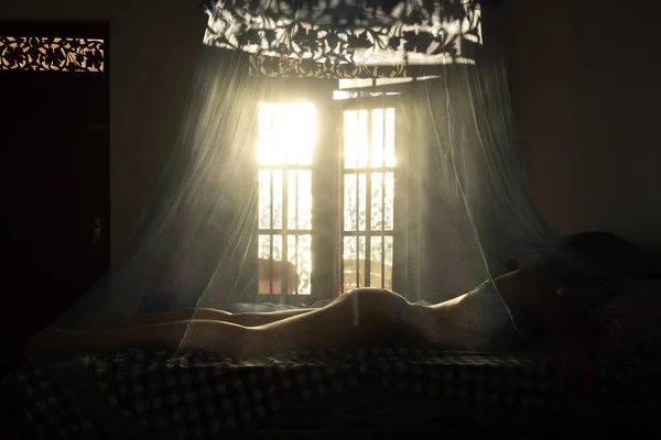 Mujer caucásica durmiendo en la cama detrás de la mosquitera — Foto de Stock