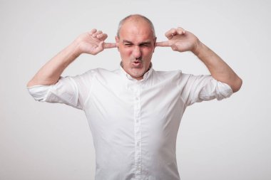 Yüksek bir ses ve gürültü nedeniyle kulakları kapanış Olgun Avrupa adam. Seni dinlemek istemiyorum.