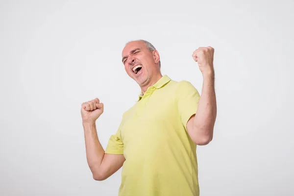 Portret van volwassen Europese man met vuisten omhoog. Hij viert winnen. — Stockfoto