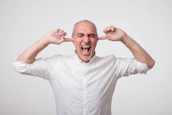 Homem europeu maduro fechando os ouvidos por causa do som alto e barulho. Não quero ouvir-te. . — Fotografia de Stock