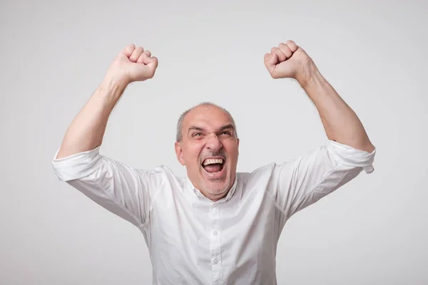 Portret van volwassen Europese man met vuisten omhoog. Hij viert winnen. — Stockfoto