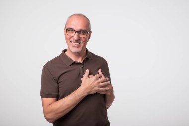 Gülümseyen ve kalp üzerinde ellerini koyarak başarılı yakışıklı bir olgun adam portresi