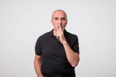 siyah t-shirt onun dudaklarında parmak ile yakışıklı yaşlı adam. Sessizlik kavramı
