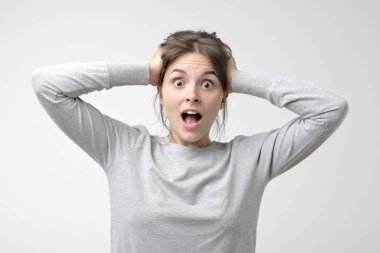 Basit t-shirt beyaz kadın kafasını elinizle tutarak nrews ile şaşırır. Haberler ve beklenmeyen sonuçlar kavramı.