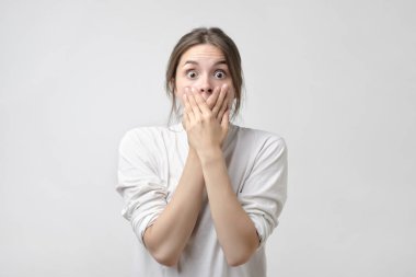 çekici, güzel ve büyüleyici, kadın kapalı ağzını çapraz eller ve geniş açık gözleri kameraya bakıyor. O gözleri inanamıyorum