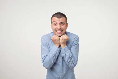 Gri arka plan üzerinde izole genç yakışıklı bir adam. Yumruklarını mutluluk derin duygusal ifadede tutan zaferini kutluyor kavramı. Stüdyo çekimi