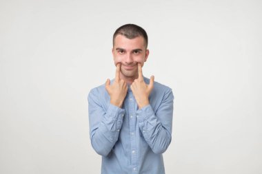 Yakışıklı delikanlı mavi gömlek yerine kötü depresif duygudurum gülümsemeye çalışıyorum. Surat. Negatif yüz duygu