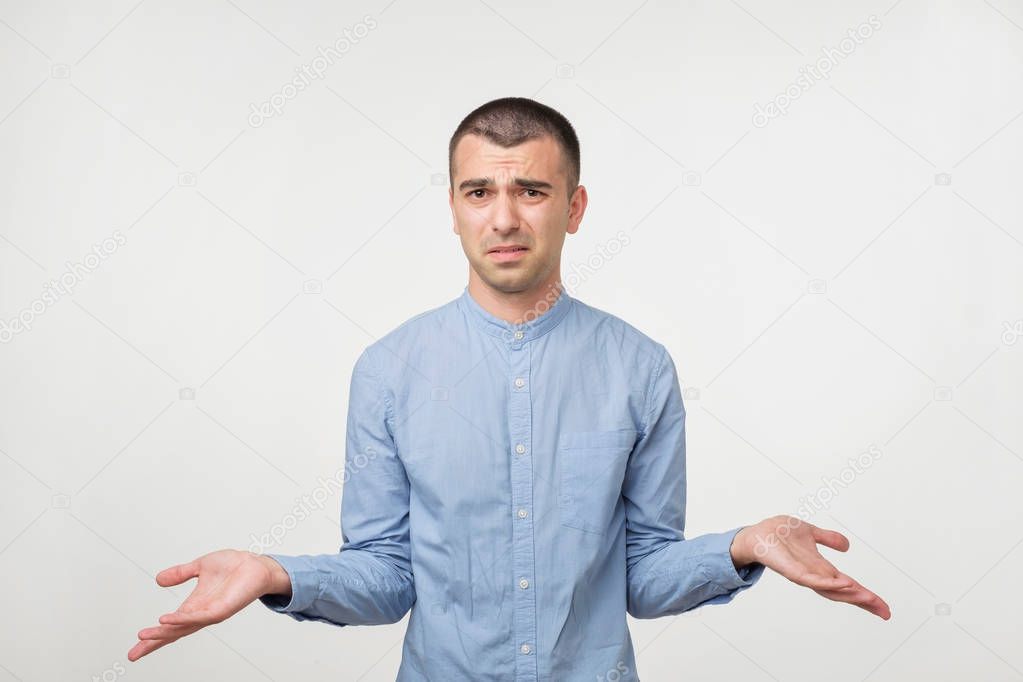 Caucasian man in blue shirt throws up his hands. He is confused with results.