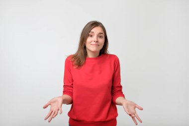 Kırmızı kazaklı ayakta genç kadın şaşkın izole üzerinde gri duvar arka plan disorientated. Karar verme kavramı. İnsan yüz ifadesi duygular