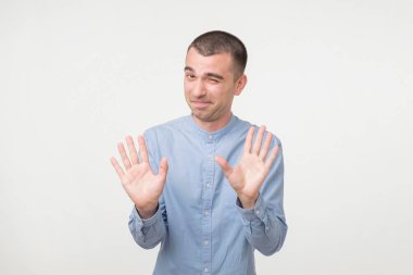 Gösterilen çekici bir adam portresi dayan hareketi ile yükseltilmiş avuç içi ve gülümseyerek, gri arka plan üzerinde duran. Bir saniye bekle, her şey farklı oldu. Duraklama için sordu