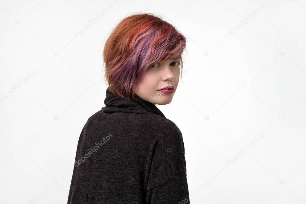 Portrait of unusual informal pretty woman with colorful hairstyle. She is turning back and look confident. Concept od self expression.