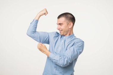 Yakışıklı orta yaş güç ve sağlıklı yaşam ifade pazı işaret mavi tişörtlü adam. Güçlü ve enerji fuul