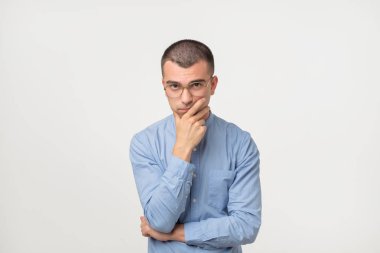 Mavi gömlek ayakta genç adam şaşkın izole üzerinde gri duvar arka plan disorientated. Karar verme kavramı. İnsan yüz ifadesi duygular