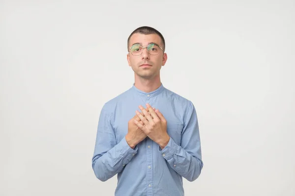 年轻的拉美裔男子在眼镜和蓝色的衬衫站在脸上简单的情绪 因为他要祈求怜悯 — 图库照片