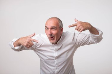 Kendisi için her iki el parmakları ile işaret beyaz gömlekli İtalyan olumlu olgun adam komik yüz buruşturma gri arka plan üzerinde yapma