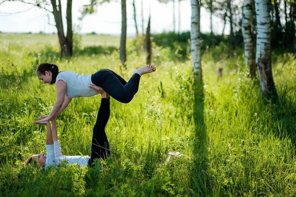 Dos mujeres en el campo haciendo ejercicio de yoga fitness juntas — Foto de Stock