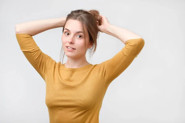 Mujer europea joven en suéter amarillo con una hermosa sonrisa en el estudio. Retrato sobre fondo gris . — Foto de Stock